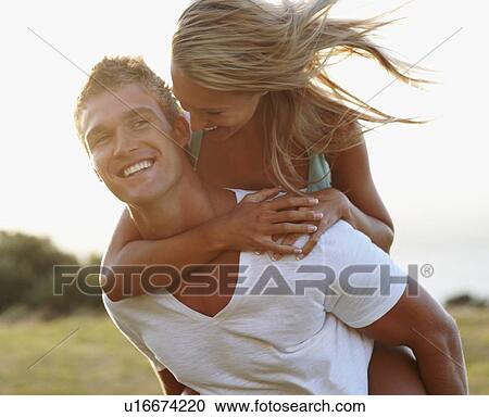 Stock Image - Man giving girlfriend a piggy back ride. Fotosearch