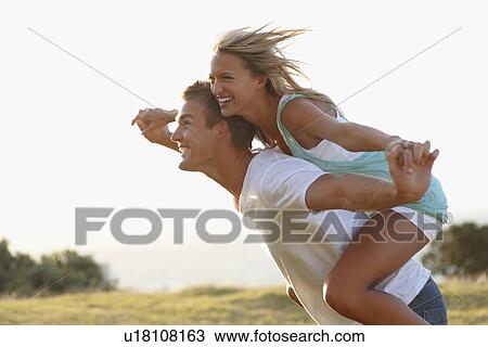 Stock Image - Man giving girlfriend a piggy back ride. Fotosearch