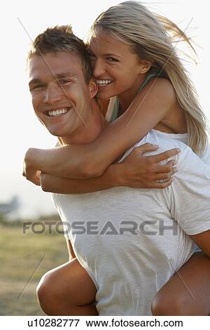 Stock Photo - Man giving girlfriend a piggy back ride. Fotosearch