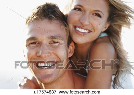 Stock Photo - Man giving girlfriend a piggy back. Fotosearch