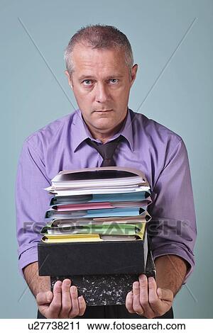 Stock Image - Man holding a stack of paper work. Fotosearch