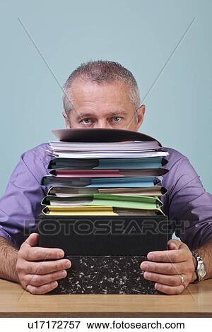 Man sitting behind a stack of paper work View Large Photo Image Stock Photo - Man sitting behind a stack of paper work. Fotosearch