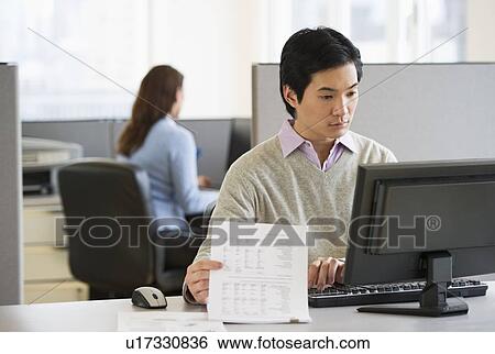 Stock Photograph - Man working in cubicle. Fotosearch