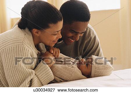 Stock Photo - Mother and father admiring their baby. Fotosearch