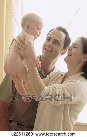 Stock Image - Mother and father admiring their newborn baby. Fotosearch