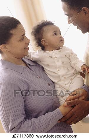 Mother and father holding their baby View Large Photo Image Stock Image - Mother and father holding their baby. Fotosearch