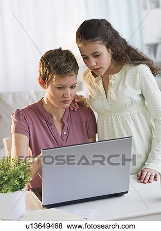 Stock Photo - Mother helping daughter with her homework. Fotosearch
