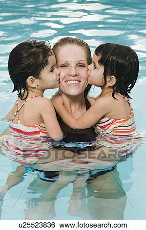 Stock Photograph - Mother holding daughters in pool. Fotosearch