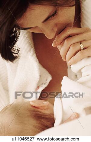 Stock Photo - Mother kissing her babies hand. Fotosearch