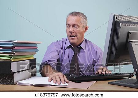 Overworked man sitting at his desk View Large Photo Image Stock Photo - Overworked man sitting at his desk. Fotosearch