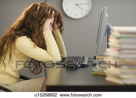 Stock Image - Overworked woman in cubicle. Fotosearch
