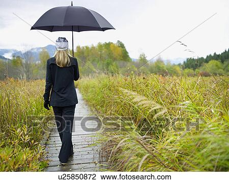 Person walking on boardwalk on rainy day View Large Photo Image Stock Image - Person walking on boardwalk on rainy day. Fotosearch
