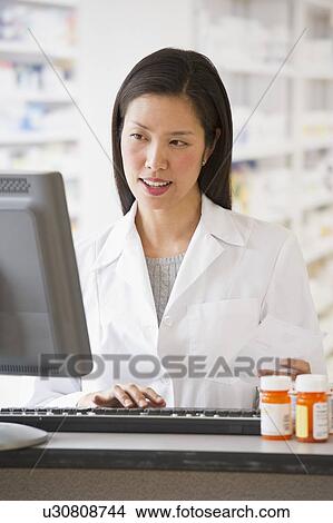 Pharmacist working on computer View Large Photo Image Picture - Pharmacist working on computer. Fotosearch