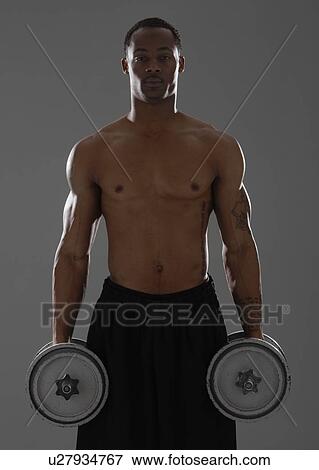 Stock Photo - Physically fit man lifting dumbbells. Fotosearch