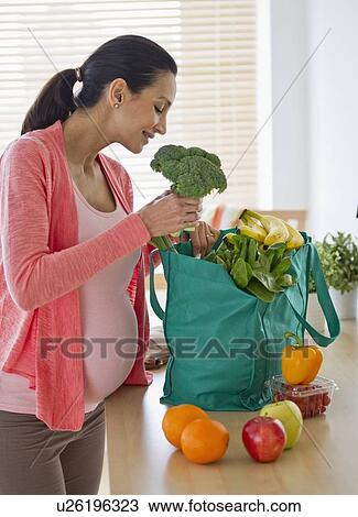 Pregnant woman unpacking groceries View Large Photo Image Stock Image - Pregnant woman unpacking groceries. Fotosearch