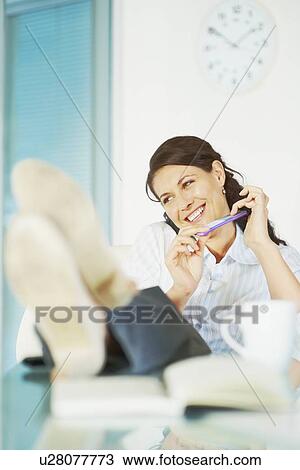 Relaxed woman sitting at desk View Large Photo Image Stock Image - Relaxed woman sitting at desk. Fotosearch