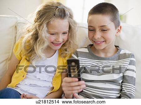 Picture - Siblings looking at cellular phone. Fotosearch