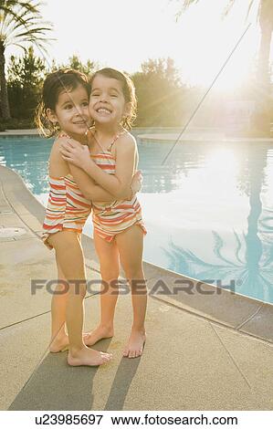 Stock Photo - Sisters standing beside pool. Fotosearch