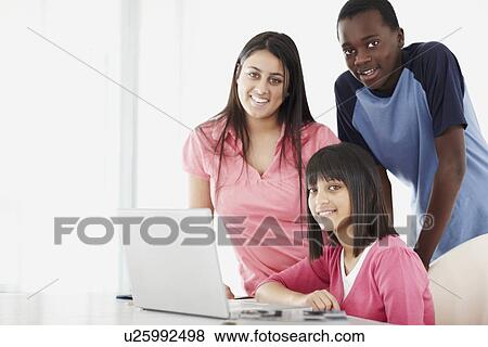 Stock Photo - Students looking at laptop. Fotosearch