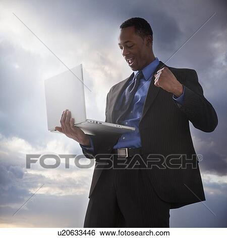 Stock Photograph - Successful businessman holding a laptop computer. Fotosearch