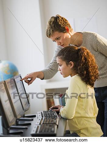 Stock Photo - Teacher helping student in computer lab. Fotosearch