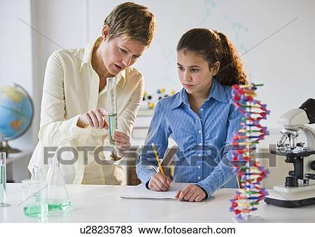 Stock Image - Teacher helping student in science lab. Fotosearch