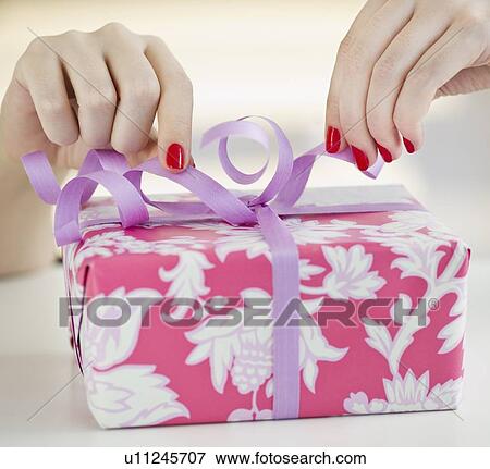 Tying a bow on a present View Large Photo Image Stock Photo - Tying a bow on a present. Fotosearch