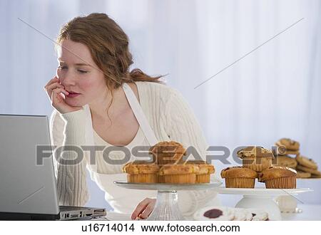 Picture - Woman baking and reading recipe. Fotosearch