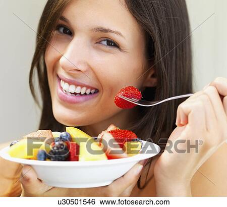 Stock Photograph - Woman eating fresh fruit. Fotosearch