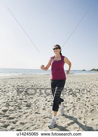 Stock Photography - Woman jogging on beach. Fotosearch