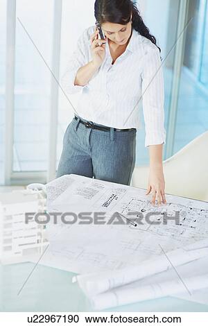 Stock Image - Woman looking at blueprints. Fotosearch