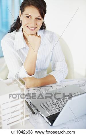 Stock Photo - Woman sitting at desk. Fotosearch