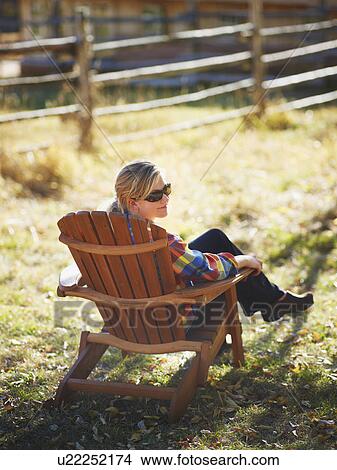 Woman sitting in Adirondack chair View Large Photo Image Picture - Woman sitting in Adirondack chair. Fotosearch