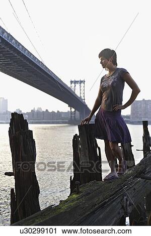 Stock Image - Woman standing beside water. Fotosearch