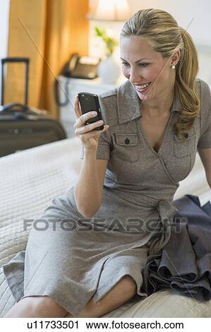 Stock Image - Woman texting in hotel room. Fotosearch