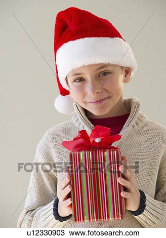 Stock Image - Young boy holding a Christmas present. Fotosearch