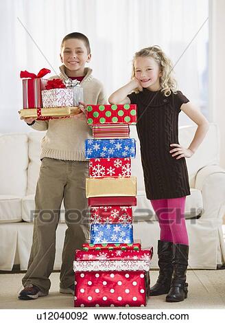 Young children beside a stack of Christmas gifts View Large Photo Image Stock Image - Young children beside a stack of Christmas gifts. Fotosearch