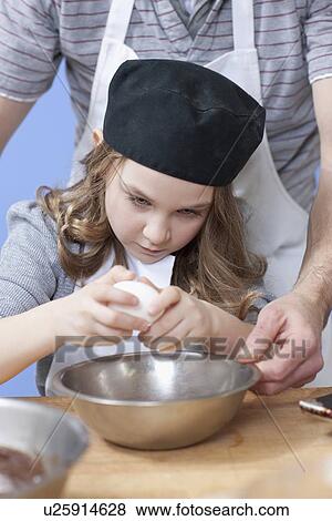 Stock Photo - Young girl cracking an egg. Fotosearch