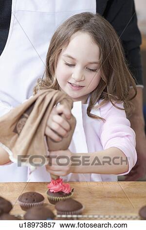 Stock Photo - Young girl decorating cupcakes. Fotosearch
