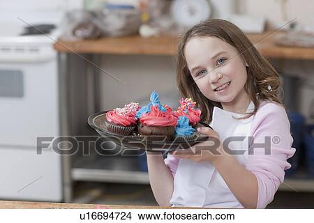 Young girl holding a plate of cupcakes View Large Photo Image Picture - Young girl holding a plate of cupcakes. Fotosearch