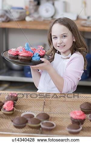 Young girl holding a plate of cupcakes View Large Photo Image Stock Photo - Young girl holding a plate of cupcakes. Fotosearch