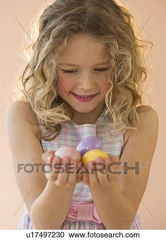 Stock Image - Young girl holding Easter eggs. Fotosearch