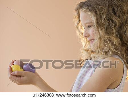 Stock Photo - Young girl holding Easter eggs. Fotosearch