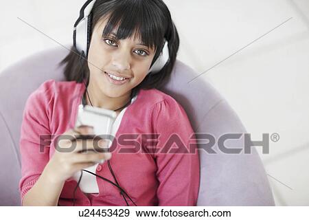 Stock Photo - Young girl listening to music. Fotosearch