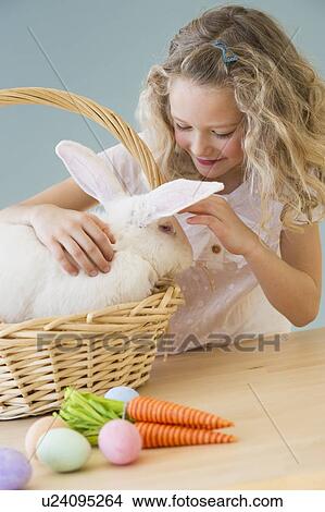 Picture - Young girl petting a rabbit in a basket. Fotosearch