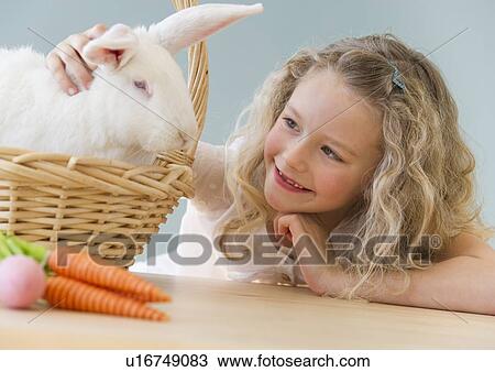 Young girl petting a rabbit in a basket View Large Photo Image Stock Image - Young girl petting a rabbit in a basket. Fotosearch