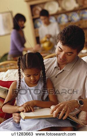 Stock Image - Young girl reading with her father. Fotosearch