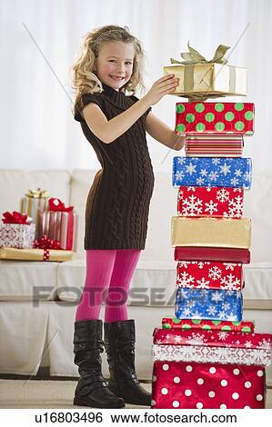 Stock Photograph - Young girl stacking Christmas gifts. Fotosearch