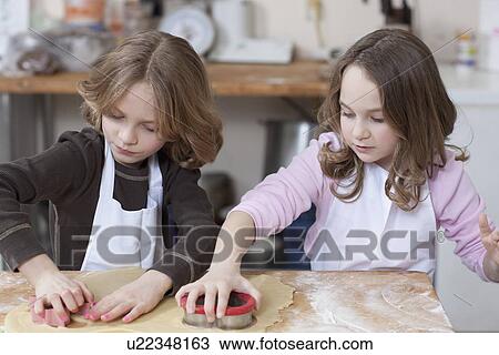 Stock Image - Young girls baking cookies. Fotosearch