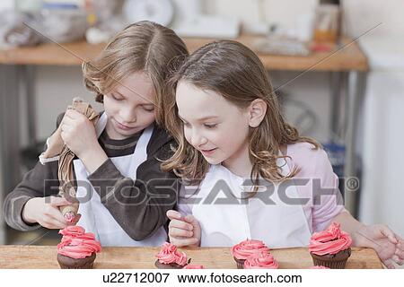 Stock Photo - Young girls decorating cupcakes. Fotosearch